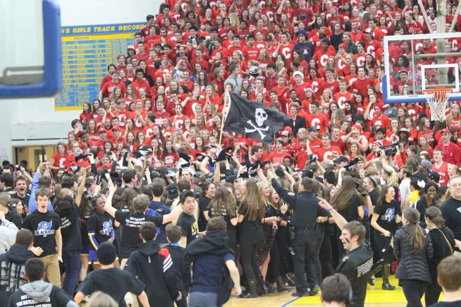 Students storm the court after Swinehart hit his half-court shot. He is visible in the bottom right with eye-black on his face. 