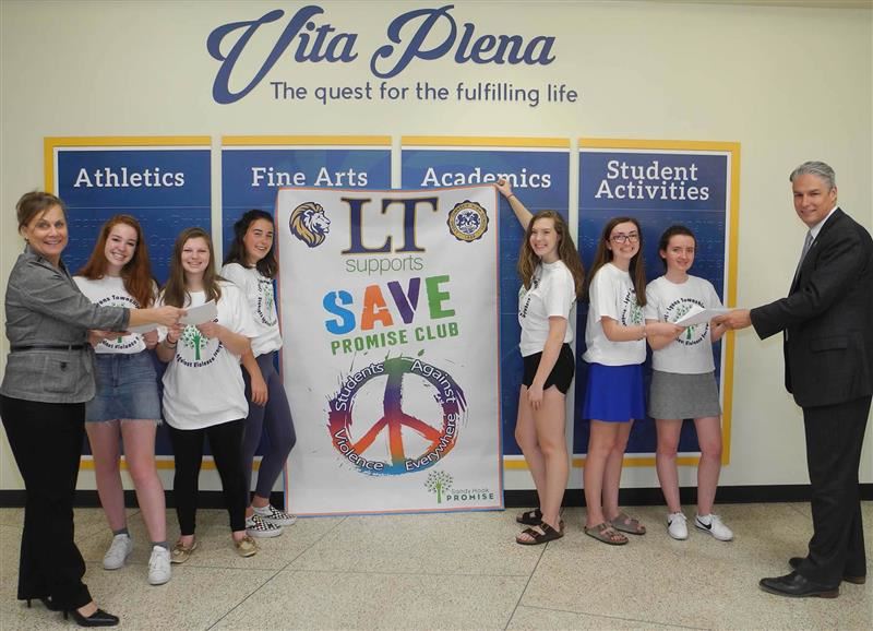 Members of the LT Save club pose with administrators Dr. Waterman and Therese Nelson in front of a sign for their club