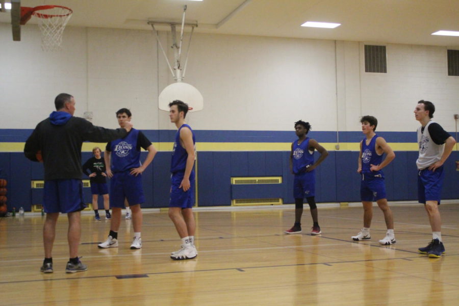 Returning varsity players watch coach Thomas Sloan describe a new defensive play (Sorice/LION).