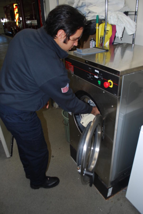 Western Springs firefighter Stefan Krkic demonstrates  safe PPE washing technique in specialized equipment to cleanse the material of harmful toxins (Smith/LION).