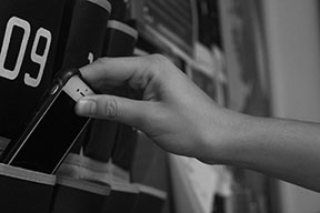 Student puts her phone in a phone pocket placed on the door of an English classroom before class (Fonseca/LION).