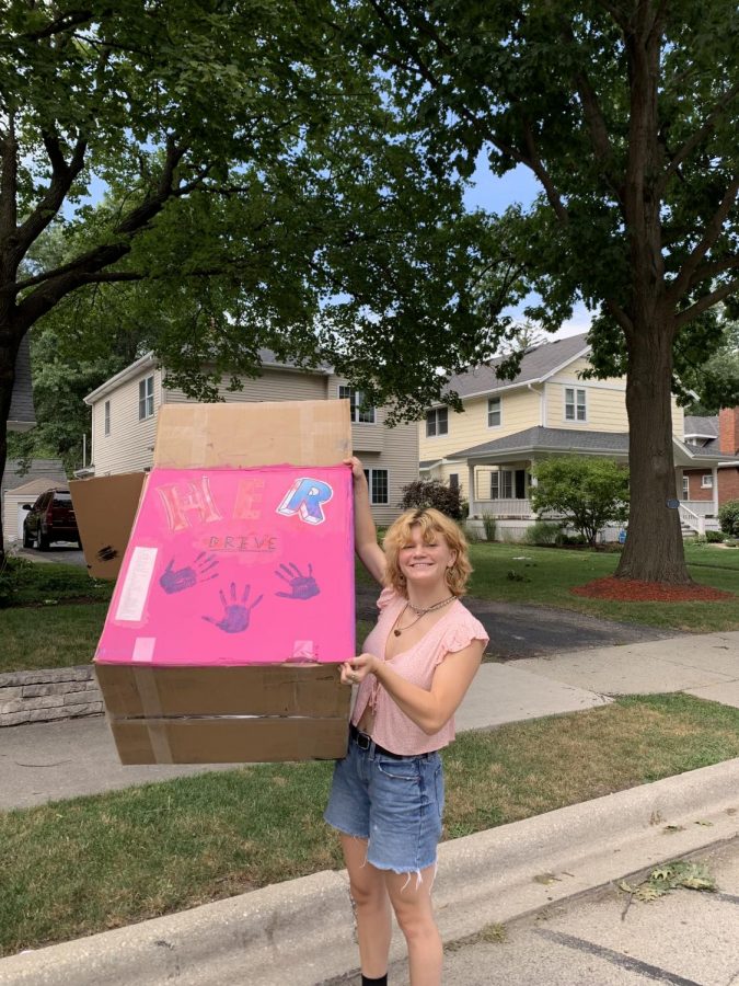 Adeline Volz poses with the HER Drive donation bin (photo courtesy of Volz). 