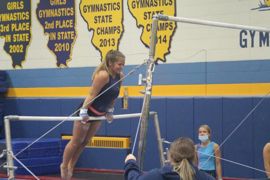 Ellie Dillon 22 smiles as she performs gymnastics trick on bar at girls practice in NC gymnastics gym (Grefenstette/LION).