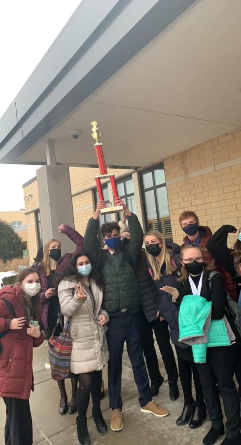 Logan Baffico ‘22 holds up tournament trophy surrounded by team members on Jan. 8 (Photo courtesy of Kaelyn Sloan)