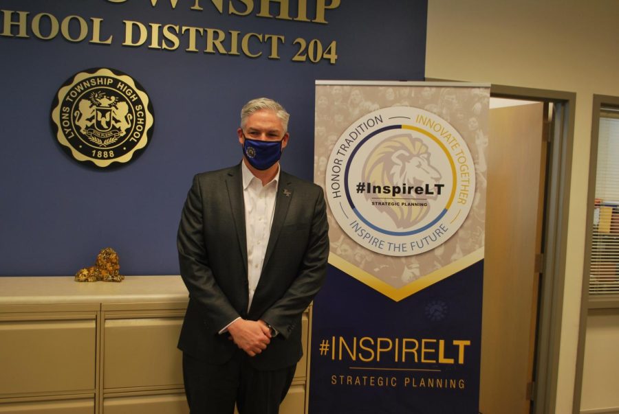 Superintendent Brian Waterman poses in front of Strategic Planning Commmitee banner in NC admin office (Morales/LION)
