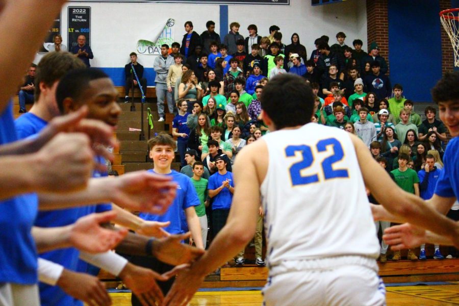 Carter Reid ‘23 runs to Will Sullivan ‘24 during lineup announcements on Jan. 28 against Riverside-Brookfield High School at NC fieldhouse (Ross/LION). 
