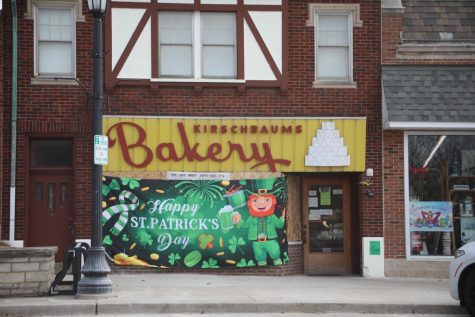 Kirschbaum’s Bakery remains open with a boarded-up front window covered with St. Patricks Day advertisement (Moran/LION).