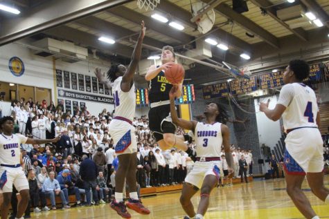 Jackson Niego ‘23 jumps into the air and scores a basket over defenders (Ludden/LION).