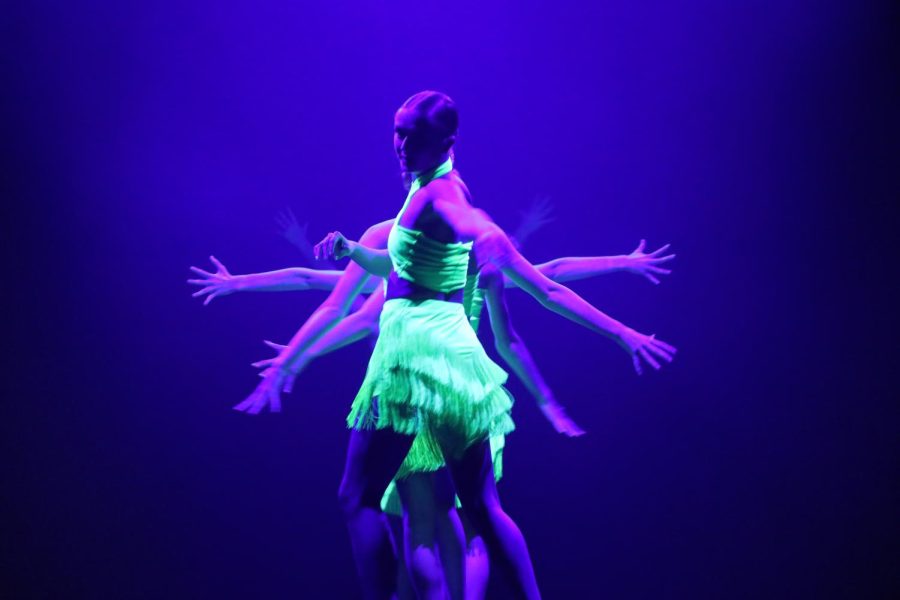 Dancers line up behind one another, create visual illusion with outstretched hands.