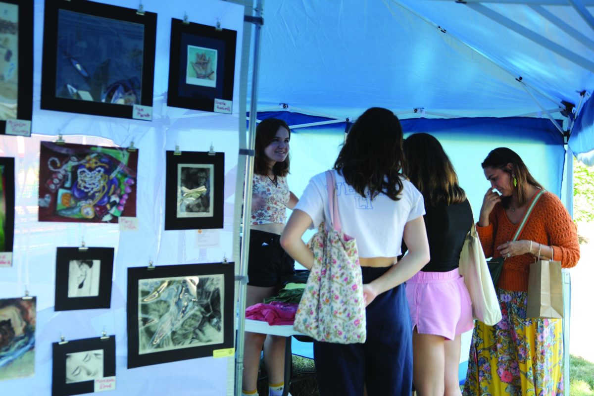 Evelyn Riordan ‘24 sells various shirts to customers exploring West End Art Festival from Sept. 9 to Sept. 10 near Stone Avenue train station. Community event showcases student artwork (James/LION). 