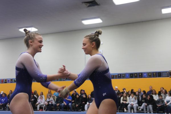Ava Hepokoski ‘25, and Elle Rockrohr ‘24 do their signature handshake before competing at their dual meet against Hinsdale Central on Jan. 17 in the NC gymnastics gym (Ruppert/LION). 
