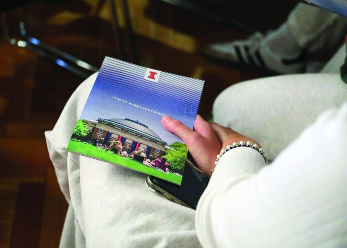 Student holds college pamphlet from the University of Illinois’s college representative during presentation (Brooks/LION).