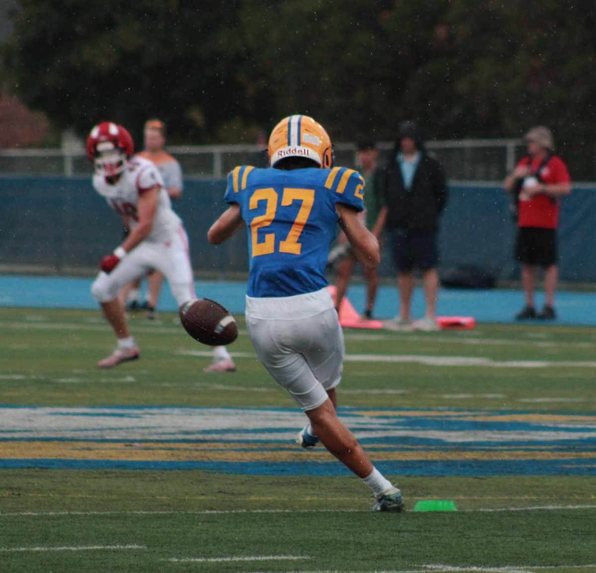 In the midst of the beginning of a rainy game, kicker Dylan Wolf ‘26 utilizes his kicking ability against the rival school, Hinsdale Central (Simmons/LION).
