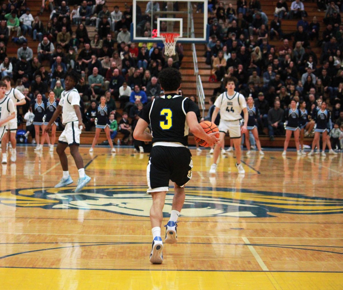 Dylan Holcer ‘26 dribbles the ball to the other side of the court, determined to score against Downers Grove South opponents (Simmons/LION). 