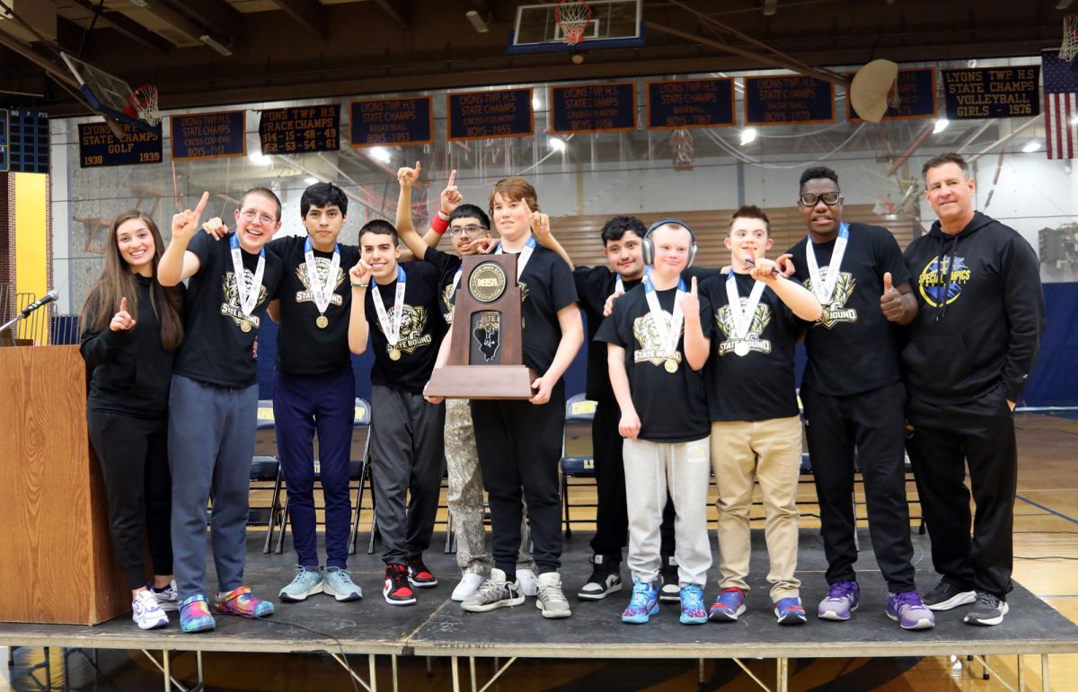 Special Olympics basketball team poses for a photo alongside coaches holding the state trophy (Brooks/LION).